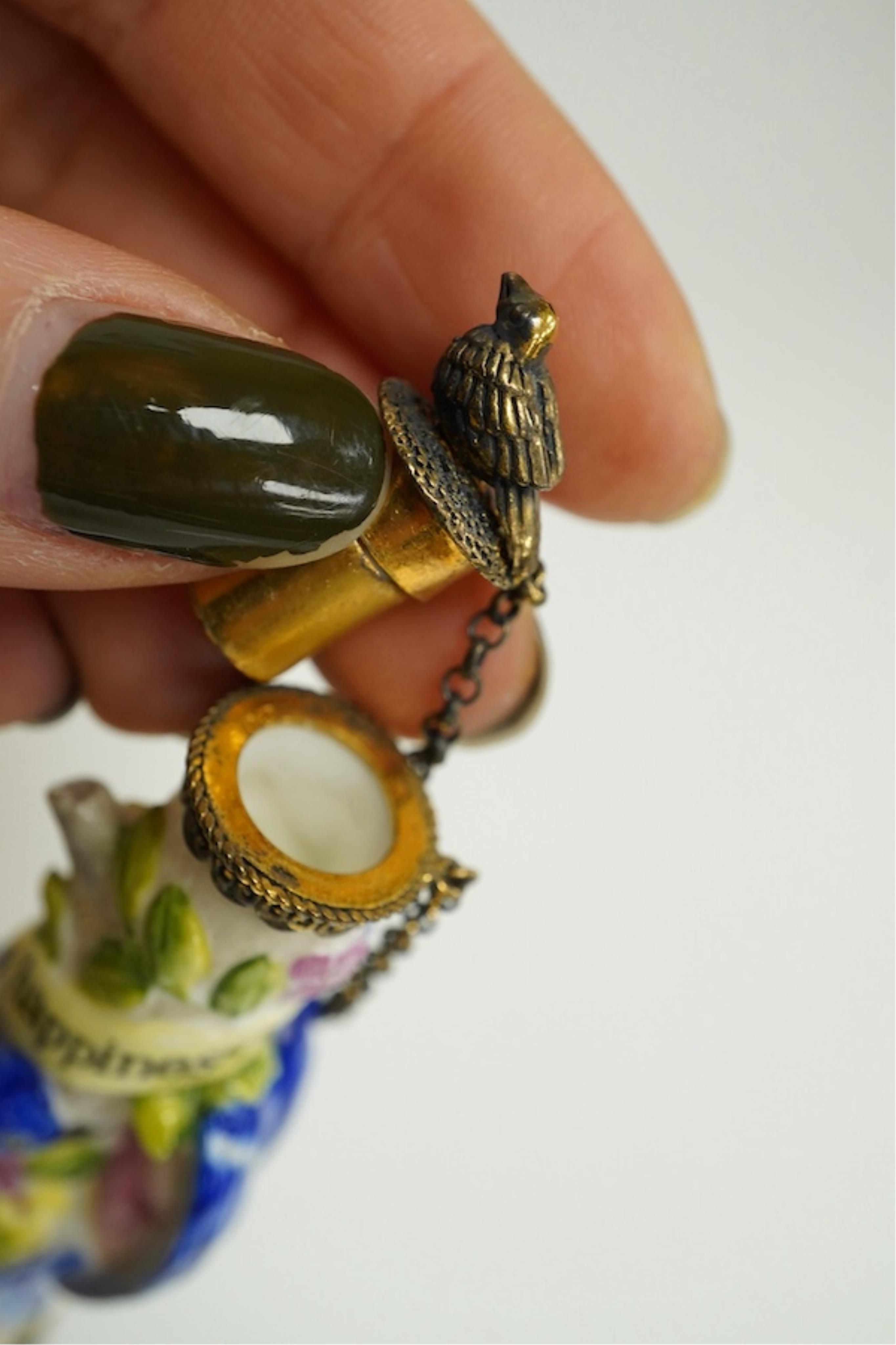 A miniature porcelain egg shaped scent bottle, on chain, two Halcyon Days scent bottles and a circular enamelled paperweight, (4). Condition - fair